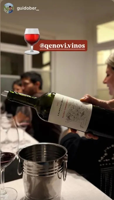 Copa de vino servida mientras alguien descorcha una botella en una cata Qenovi